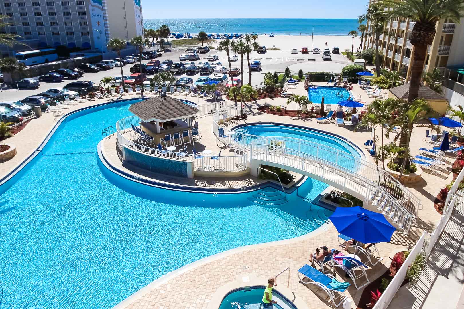 A peaceful outdoor swimming pool and the nearby beach at VRI's Coral Reef Beach Resort in St. Pete Beach, Florida.